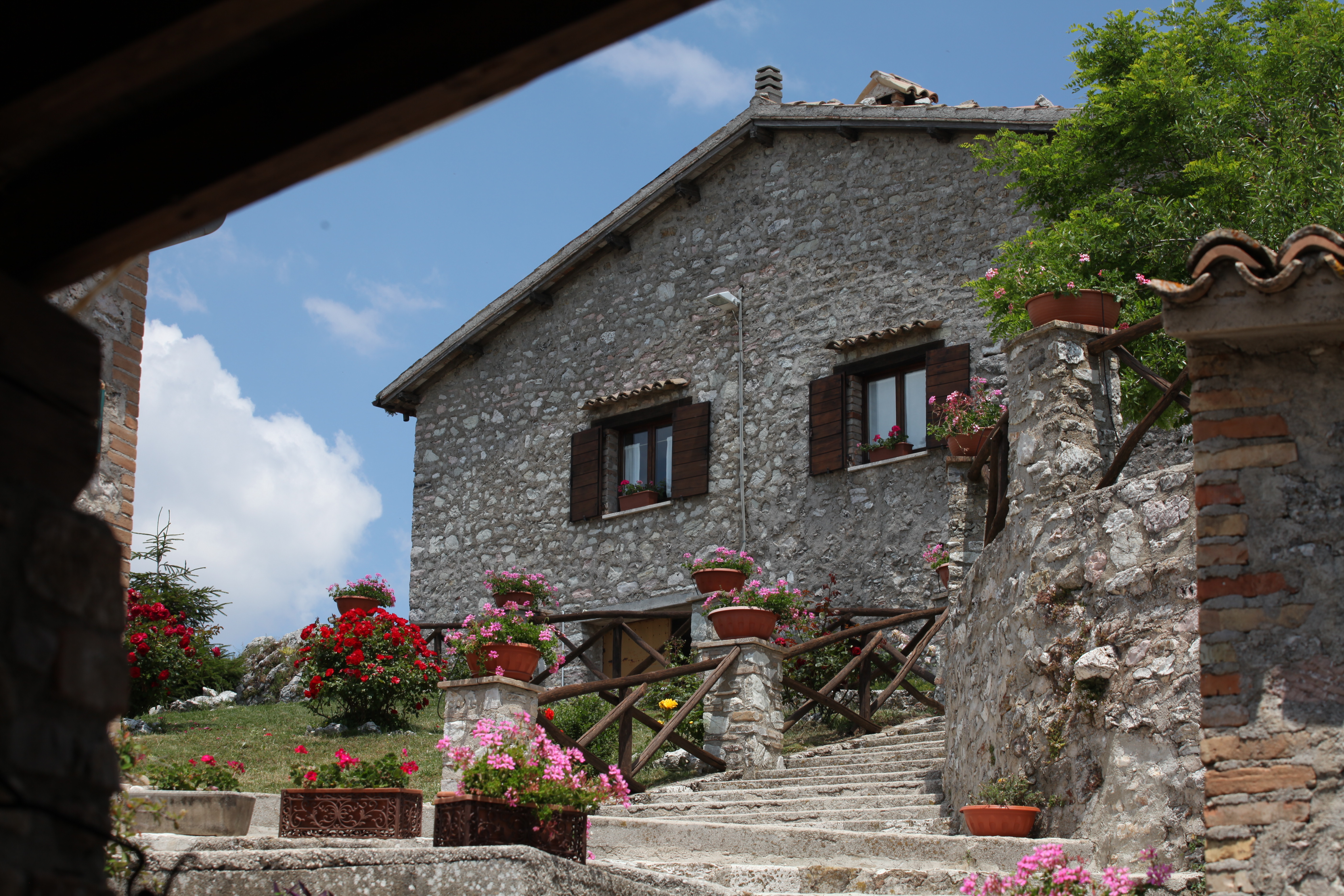 Un agriturismo caratteristico circondato da piante verdi e un bel panorama dell'Umbria.