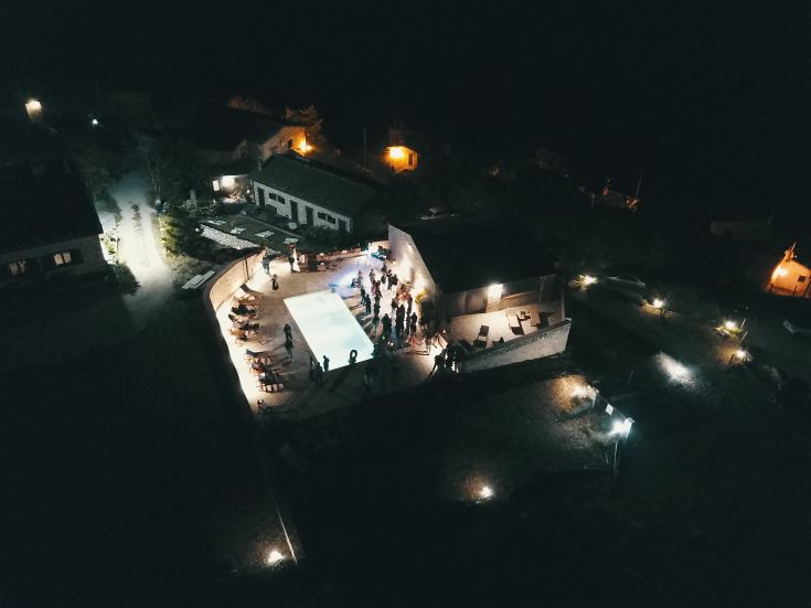 Una serata festiva in agriturismo, con piscina illuminata e un'atmosfera conviviale.
