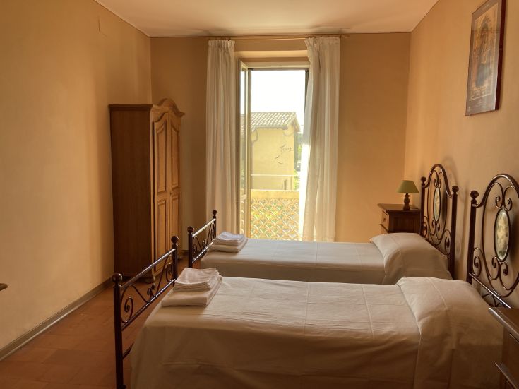 Quiet room with two single beds, well-lit by natural light and overlooking the well-maintained garden.