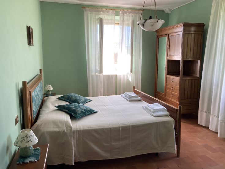 Spacious and well-lit room featuring a double bed and wooden furniture, perfect for a peaceful stay.