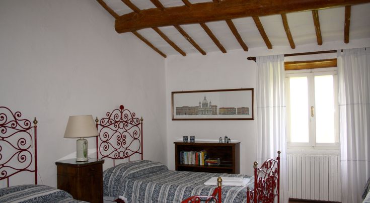 Rustic room with single beds, offering panoramic views of the Martani mountains.