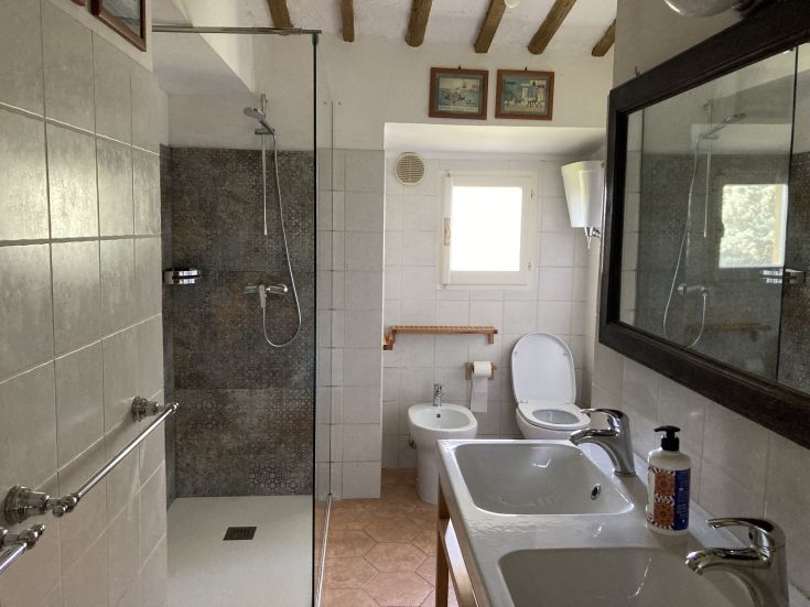 Modern bathroom featuring a walk-in shower and two sinks, designed in a simple, contemporary style.