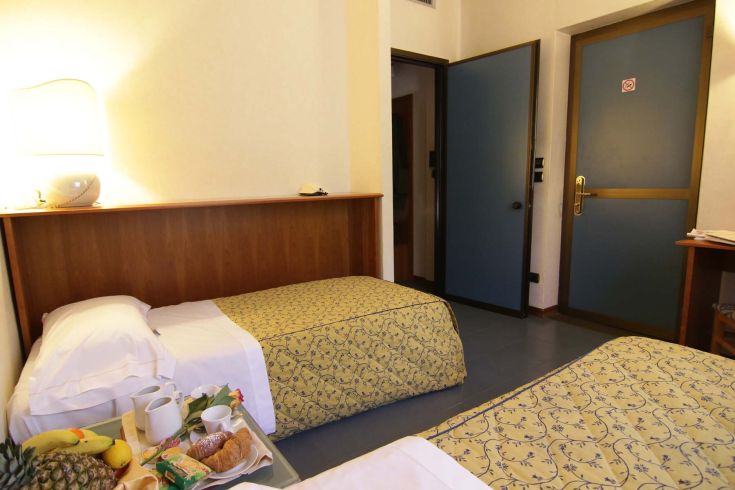 Hotel room with two beds, featuring simple and bright furnishings, ideal for a comfortable stay.
