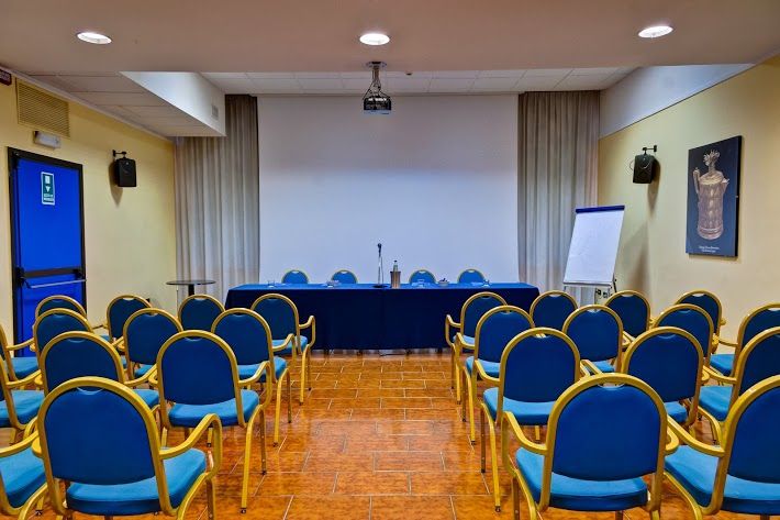 A conference room with blue chairs arranged around a central table for presentations.