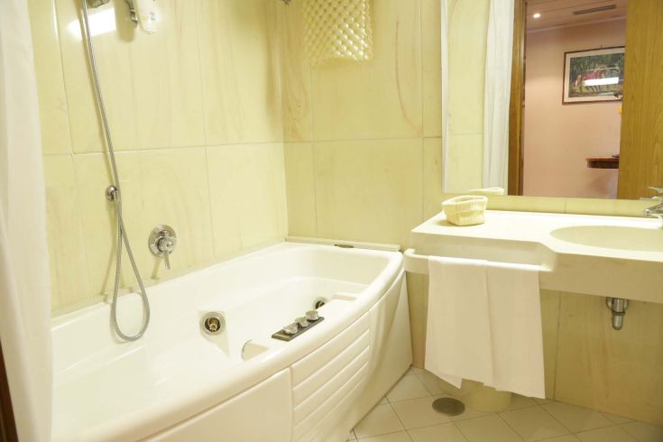 A peaceful hotel bathroom in Terni featuring a relaxing jacuzzi tub surrounded by greenery.
