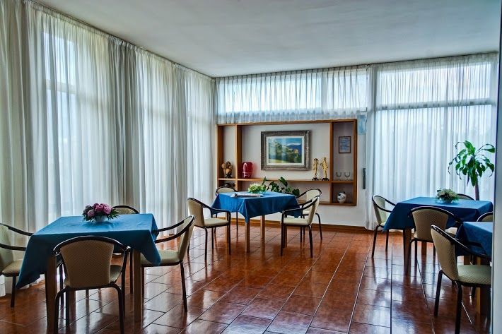Inside a hotel building, featuring tables and large windows creating a bright, welcoming environment for meetings and relaxation.
