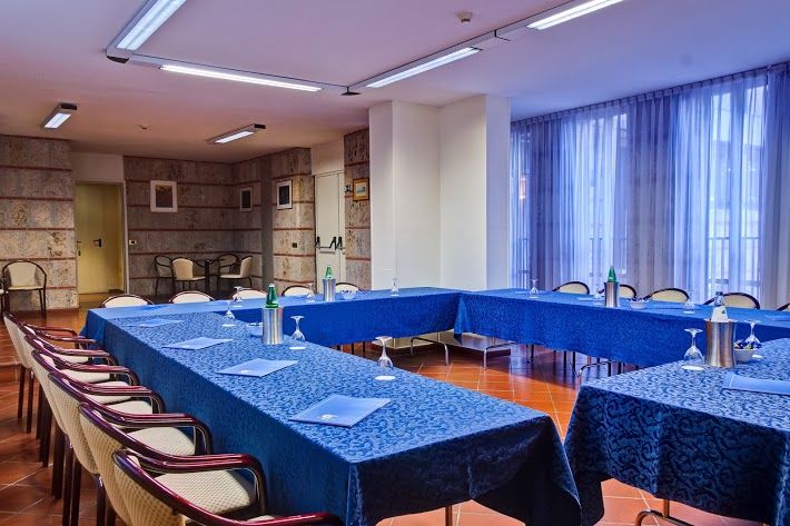 Interior of a building featuring a meeting room with blue tables and conference equipment.