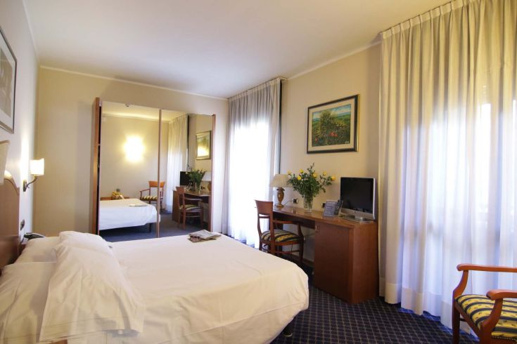 Bright and simply furnished hotel room with a double bed and desk, perfect for a stay in Terni.