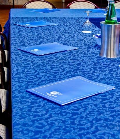 A formal meeting setup with a blue tablecloth, equipped with materials for a serious atmosphere.