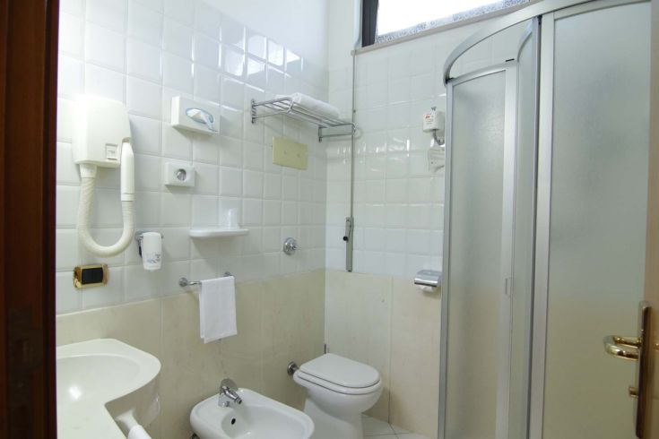 A simple and practical bathroom with a shower, sink, and toilet, ideal for everyday use.