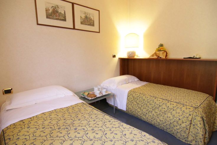 Simple and bright hotel room with single beds, perfect for a peaceful stay.