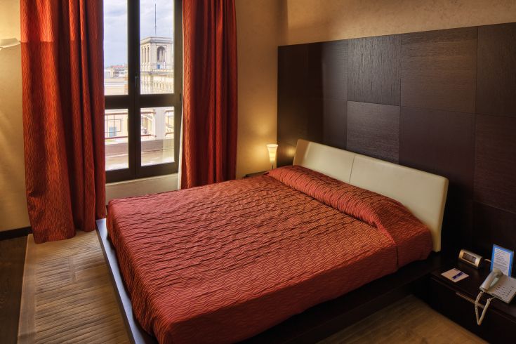 Modern hotel room with a double bed and city view, perfect for a peaceful stay.