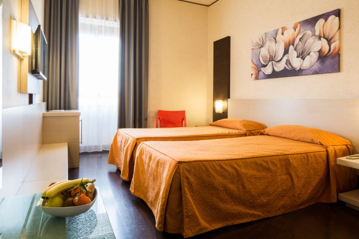 Simple and functional room at Hotel Valentino, featuring twin beds and understated decor.