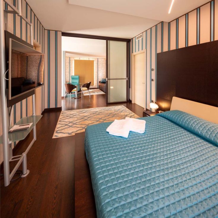 Simple hotel room with a double bed and connection to the living area.