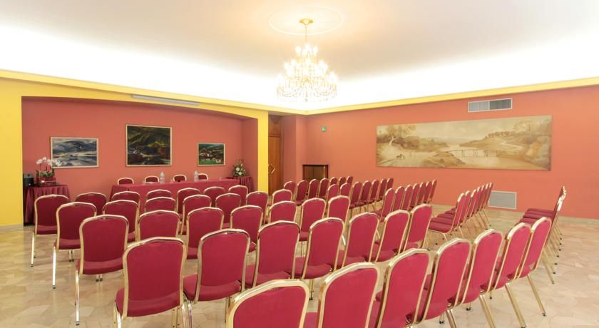 Uno spazio conferenze semplice con sedie rosse disposte in modo ordinato, adatto a eventi e incontri.