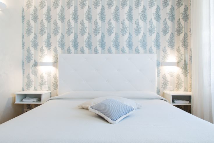 Camera ampia con letto matrimoniale, arredi semplici e decorazioni sulle pareti. Presenza di comfort moderni.