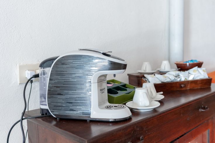 Macchina da caffè contemporanea con tazze e dolci su un tavolo in legno.