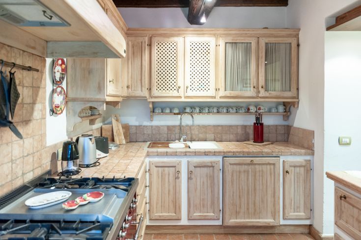 Cucina con mobili in legno e piano di lavoro in ceramica. Spazio accogliente e familiare.