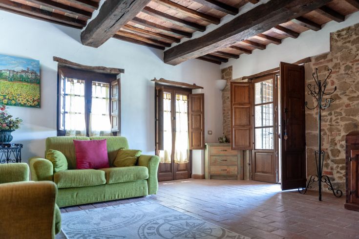 Ambiente confortevole con un divano verde e ampie finestre che lasciano entrare la luce naturale.