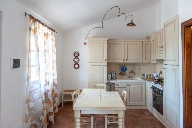 Una cucina ben illuminata e confortevole, caratterizzata da mobili chiari e dettagli in tonalità calde.