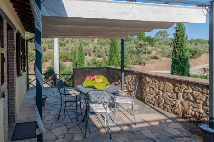 Spazio esterno dell'agriturismo Poggio del Pero, circondato da colline e piante di ulivo.