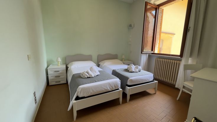 Gemütliches Zimmer in einem historischen Gebäude mit Einzelbetten. Ideal für einen ruhigen Zwischenstopp.