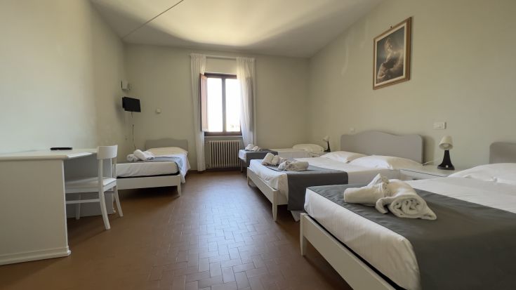 Geräumiges Zimmer in einem alten Gebäude, ausgestattet mit Einzelbetten und einem Schreibtisch, perfekt zum Entspannen.