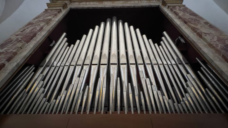 Eine Vintage-Orgel mit Metallpfeifen, die in einer historischen Umgebung steht.