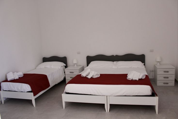 Einfaches Zimmer mit Einzelbetten und weißen Bettlaken, ideal für einen ruhigen Aufenthalt.