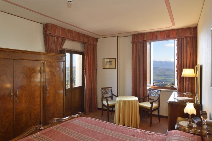 Simple room with a view of the hills, decorated in traditional style and equipped with essential comforts.