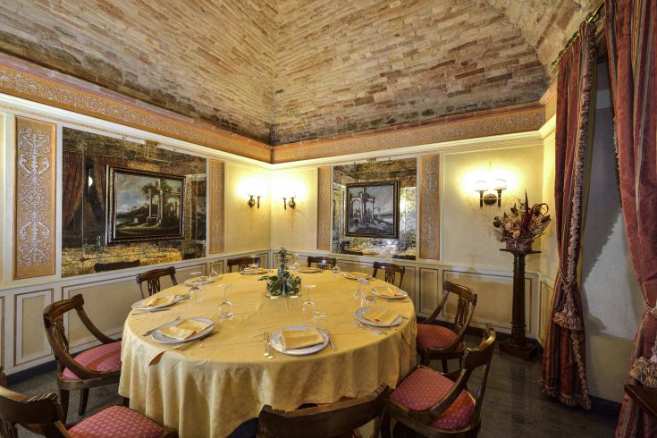 A restaurant with a minimalist design, featuring a round table and simple decorations. Walls adorned with paintings and a high ceiling.