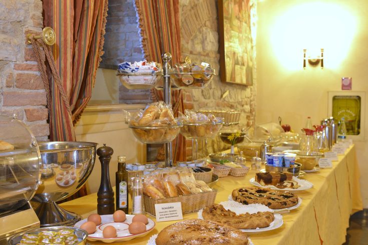 Discover a diverse breakfast buffet with pastries, fresh bread, and local products in the cozy setting of Todi.