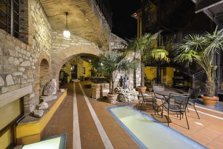 A historic hotel courtyard featuring stone arches and lush greenery, perfect for relaxing moments.