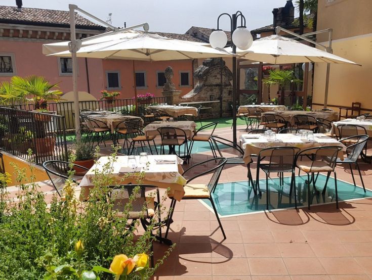 Outdoor restaurant with tables, umbrellas, and a simple yet comfortable setting in a historic context.