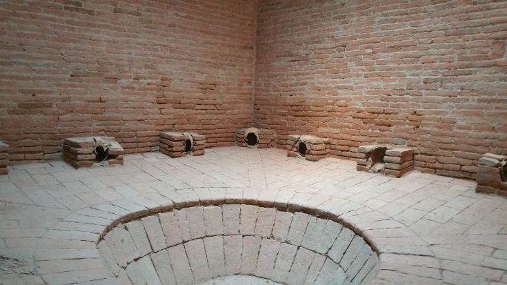 Interior of a building with brick walls, featuring openings and circular arches that highlight its historical architecture.