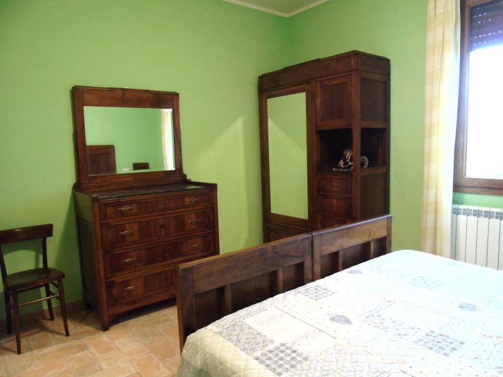 Une chambre simple avec des meubles en bois et des murs d'un vert clair.