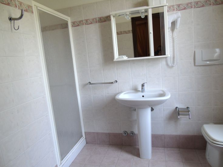 Une salle de bain moderne avec douche, lavabo et toilettes, présentée dans un style propre et pratique.