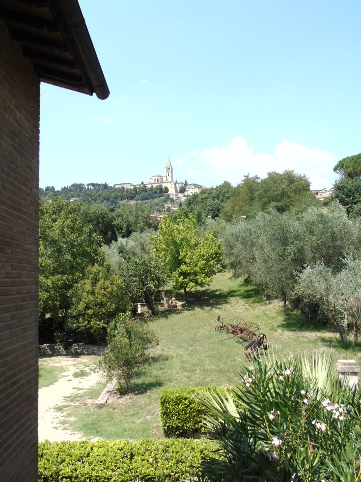 Vue sur des collines vertes avec un vieux palais niché dans la paisible nature ombrienne.