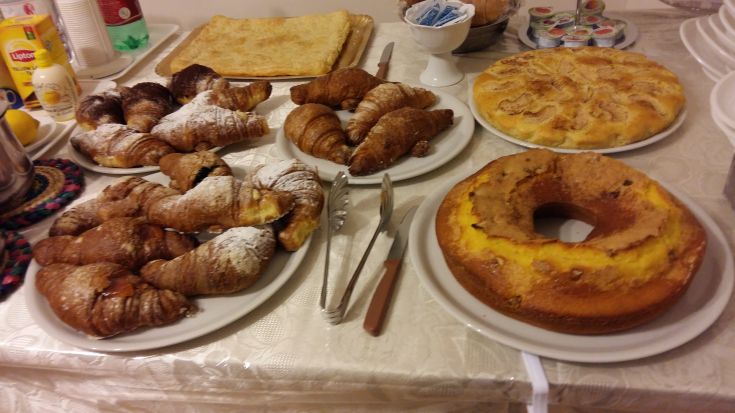 Une table dressée avec des pâtisseries traditionnelles et des croissants, idéale pour un copieux petit-déjeuner.