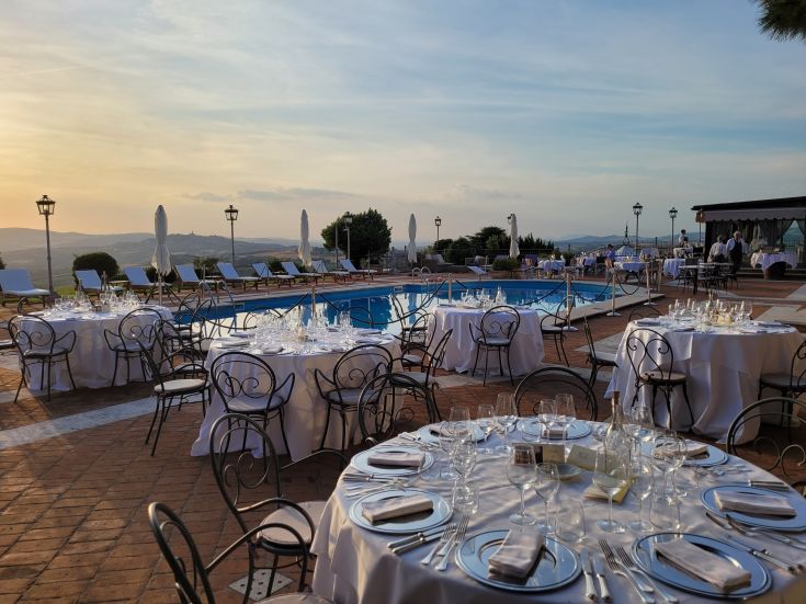 Elegant outdoor dinner setting with a stunning countryside view and a glowing pool.