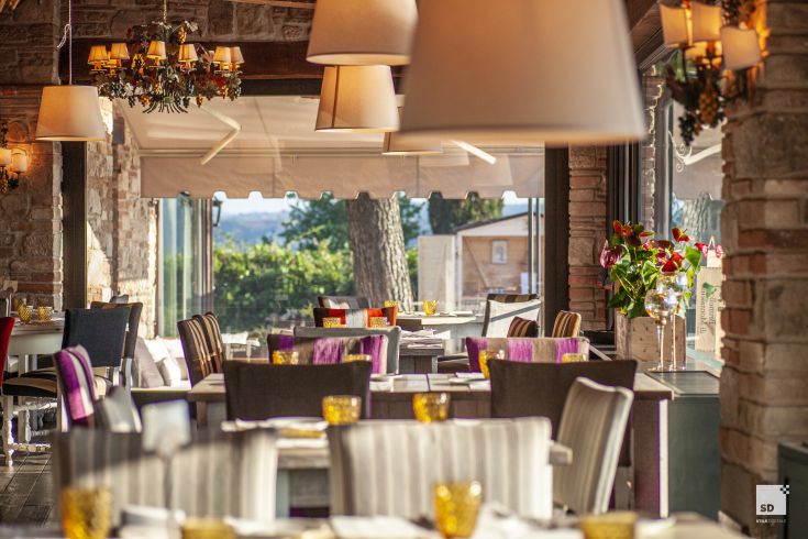 Simple restaurant with stone and wood details, overlooking the Umbrian countryside and well-maintained furnishings.