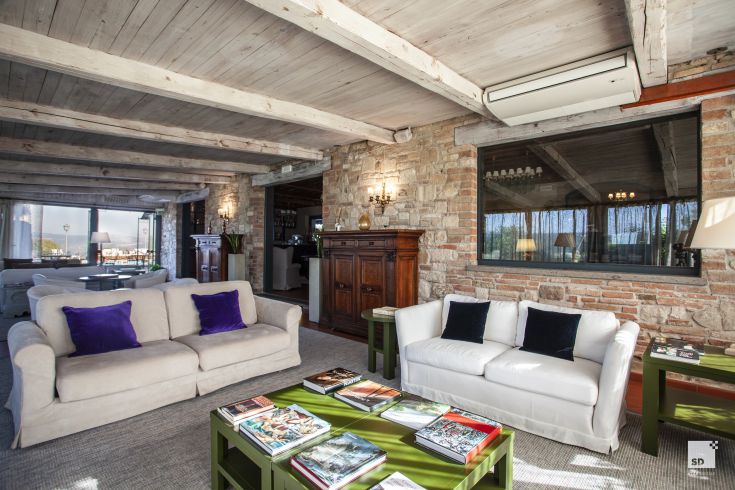 Living room of a large building with modern and classic furniture, illuminated by large windows.