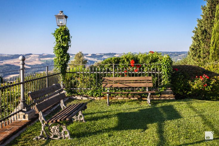 Well-maintained garden with wooden benches and a view over the Umbrian countryside.