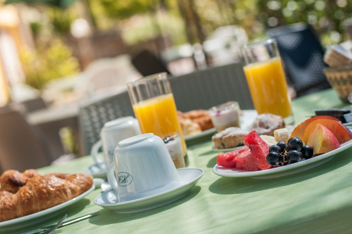 A simple breakfast featuring pastries, fruit, and orange juice served in a cozy and comfortable setting.