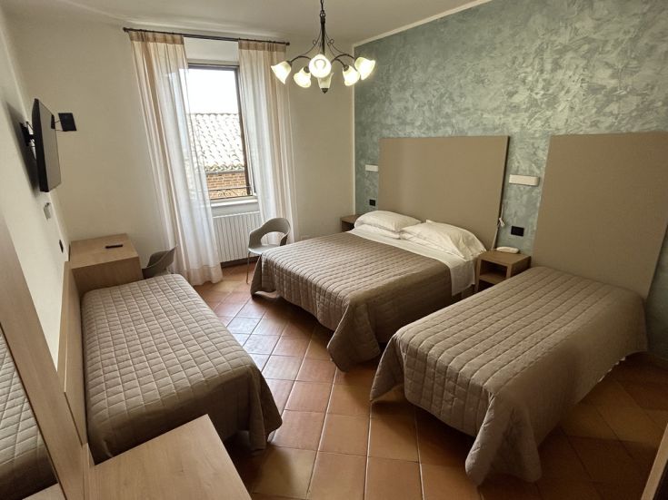 Camera semplice di un edificio, con letti singoli e comfort moderni, ideale per un soggiorno rilassante.