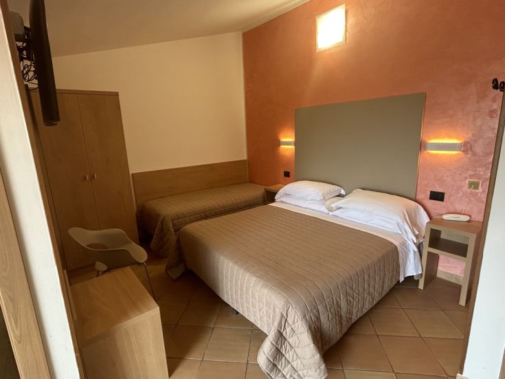 Camera semplice con letti singoli e matrimoniali, ideale per un soggiorno tranquillo.