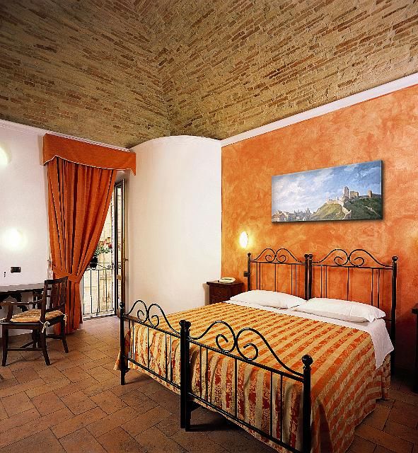 Camera in un palazzo con letto matrimoniale e colori caldi, adatta per un soggiorno tranquillo.