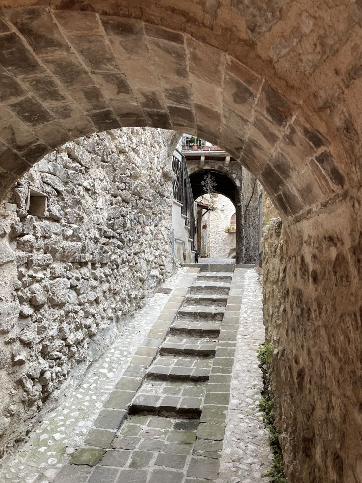 Eine Treppe in einem historischen Dorf, umgeben von alten Mauern.