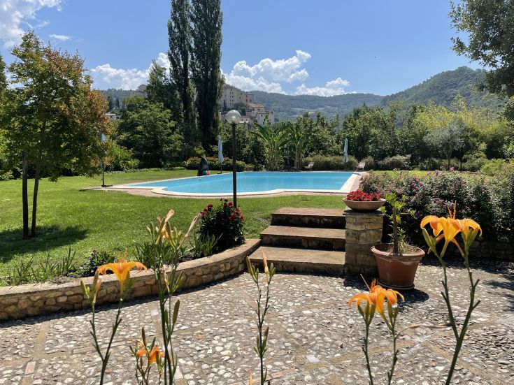 Im Borgo San Valentino wird ein Pool von einem gepflegten Garten mit grüner Vegetation umgeben, ideal zum Entspannen.