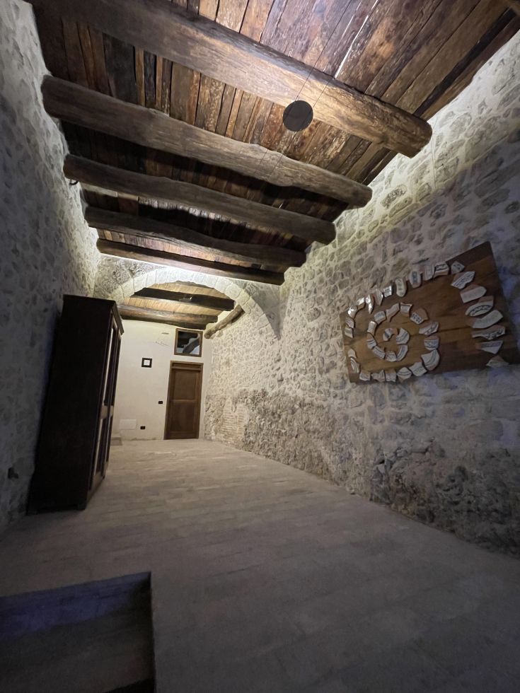 Innenbereich eines Gebäudes im Borgo San Valentino, mit Holzbalken und Steinwänden.